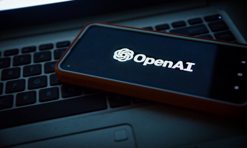 Smartphone con logo OpenAI sopra ad un laptop